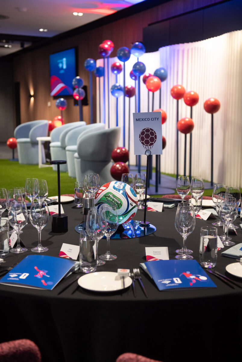 A stage and dining table decorated with painted footballs for a corporate event.