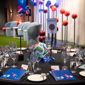 A stage and dining table decorated with painted footballs for a corporate event.
